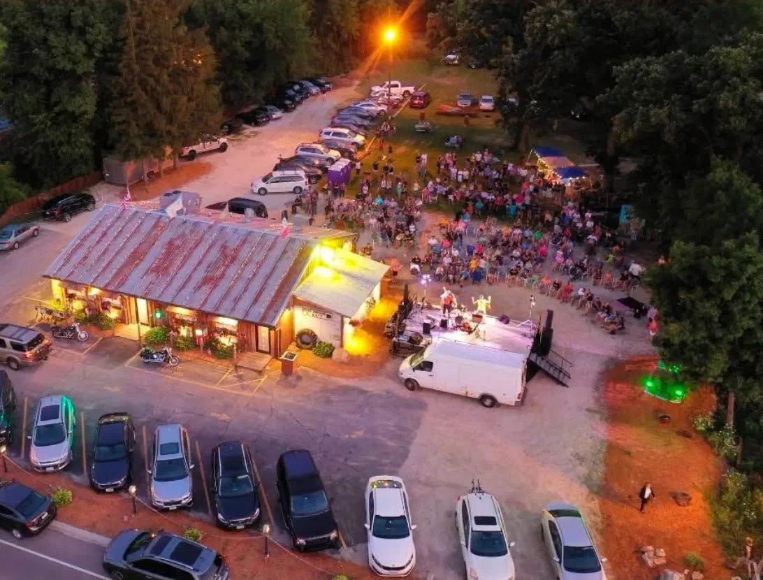 Aerial view at dusk of Edith Lucielle's rust-roofed shack, with a live band playing to a crowd out back