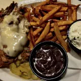 Prime rib French dip with melted cheese on a toasted hoagie, fries, au jus and cottage cheese