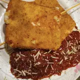 Two golden fried mozzarella wedges over marinara with shredded parmesan