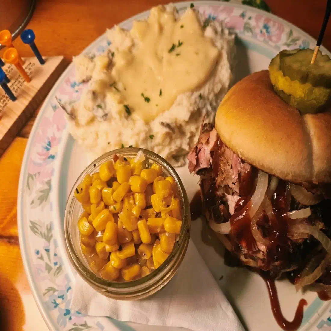 Hickory smoked pulled pork sandwich with grilled onions and BBQ sauce, mashed potatoes and corn