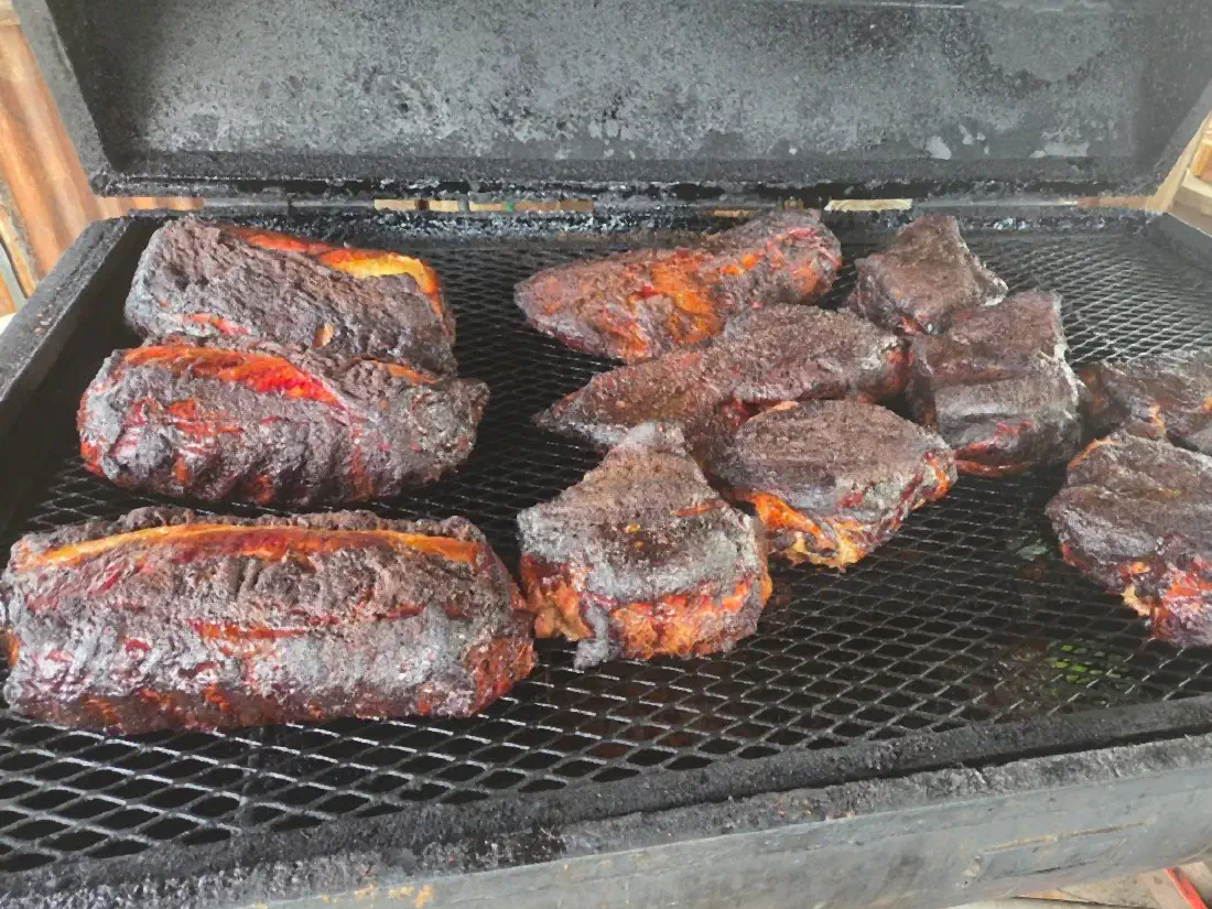 Rubbed and smoked meats resting on the grate of a big offset smoker